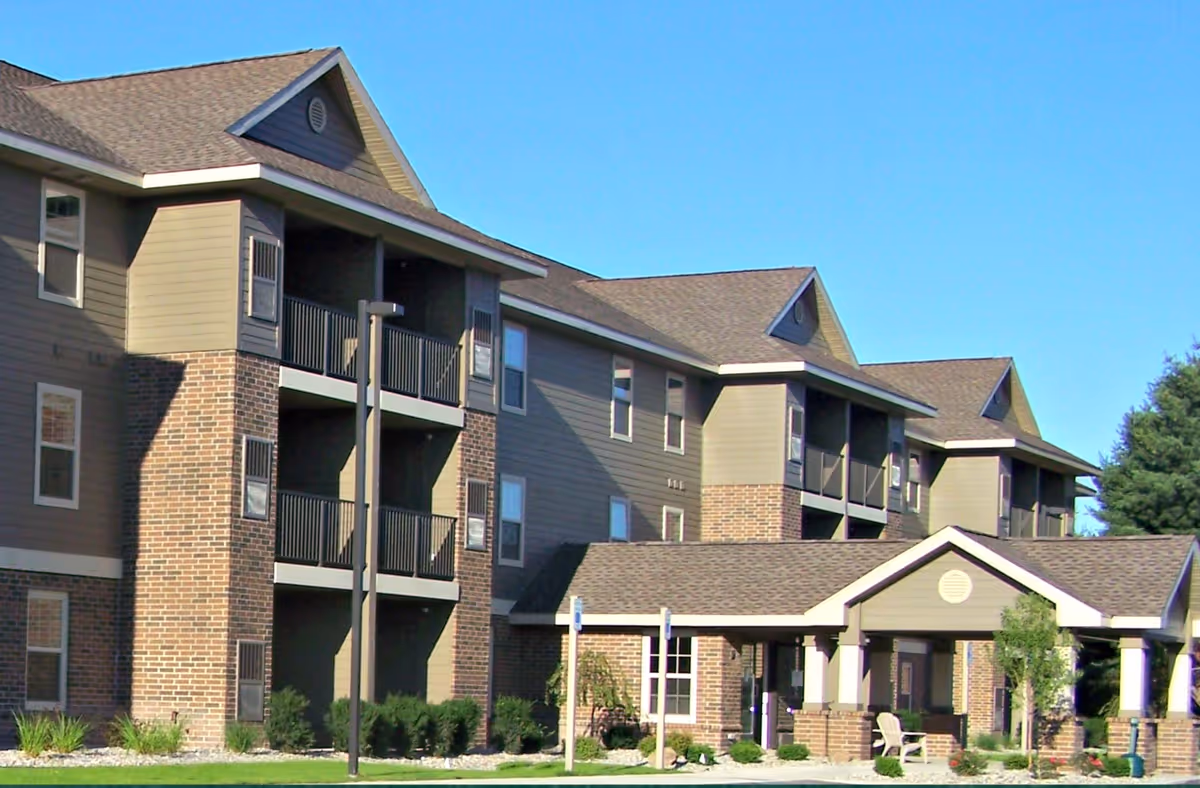 Front exterior of a multi-story senior residence with balconies and a covered entrance portico.