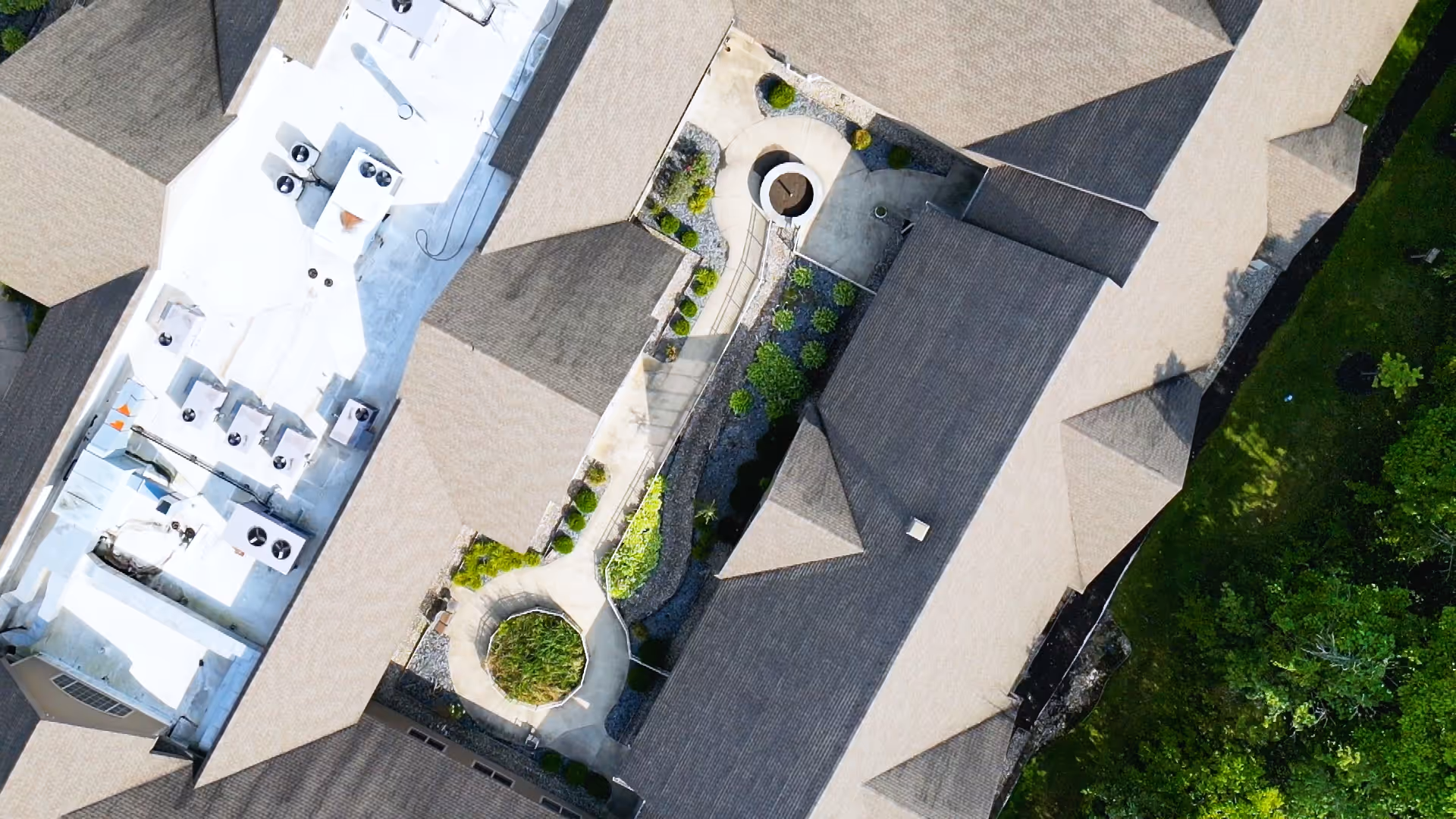 Aerial view of the roof and outdoor courtyard area of a senior living facility with pathways, greenery, and multiple roof sections.