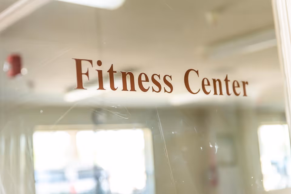 Glass door labeled "Fitness Center" with a blurred gym interior visible through the glass.
