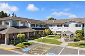 Two-story senior living facility exterior with a covered entrance, courtyard gazebo, and handicap parking spaces.