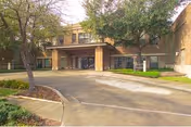 Exterior view of Alameda Oaks Nursing Center with driveway, entrance, and surrounding trees.