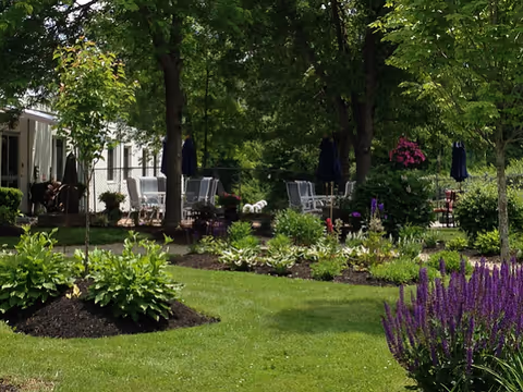 Outdoor garden patio with tables, chairs, and trees at a nursing center.