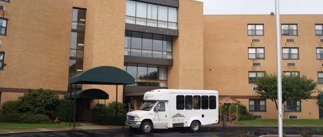 White shuttle bus parked in front of DuBois Village Personal Care Community building.