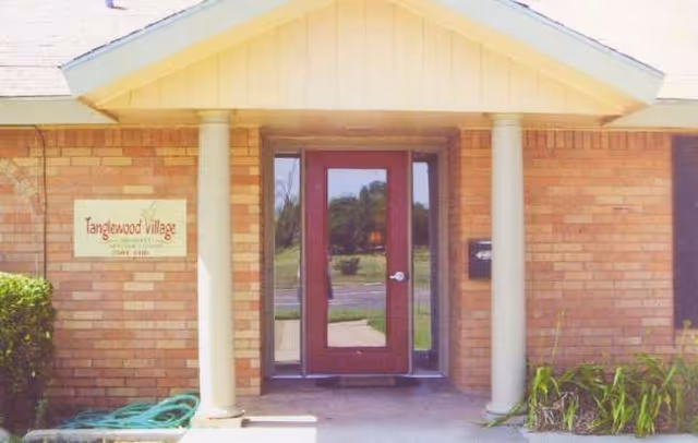 Brick exterior entrance of Tanglewood Village with a double glass door and columns.