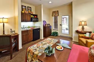 Bright living room in Beacon Hill senior facility with sofa, coffee table, and kitchenette.