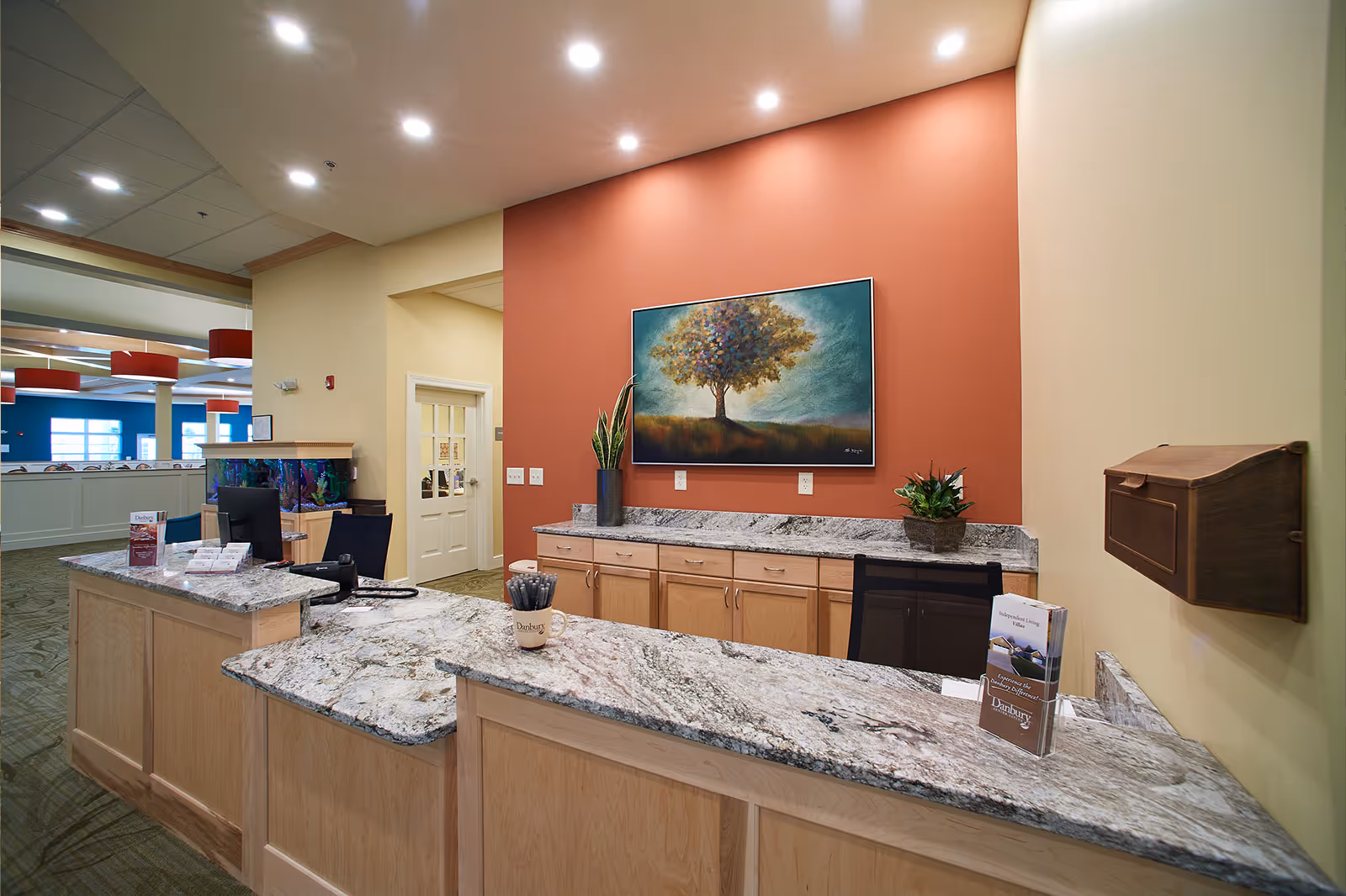 Reception desk and lobby area with granite countertops, a painting on an accent wall, and office chairs.