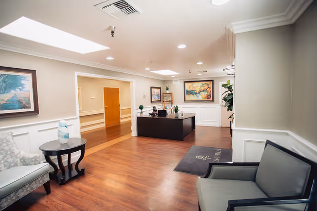 Reception lobby with seating, a front desk, artwork on the walls, and hardwood floors.