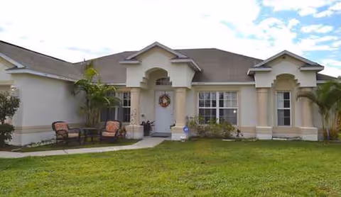 A single-story senior living building with a manicured lawn and front entrance.