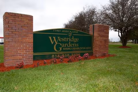 Large green Westridge Gardens nursing and rehabilitation center sign mounted between two brick pillars on a grassy lawn.