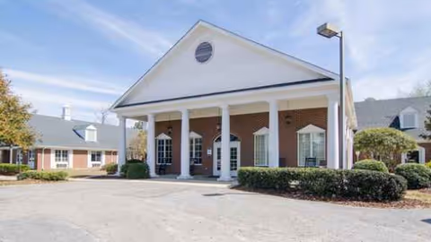 Front view of a brick senior living facility with white columns and entrance.