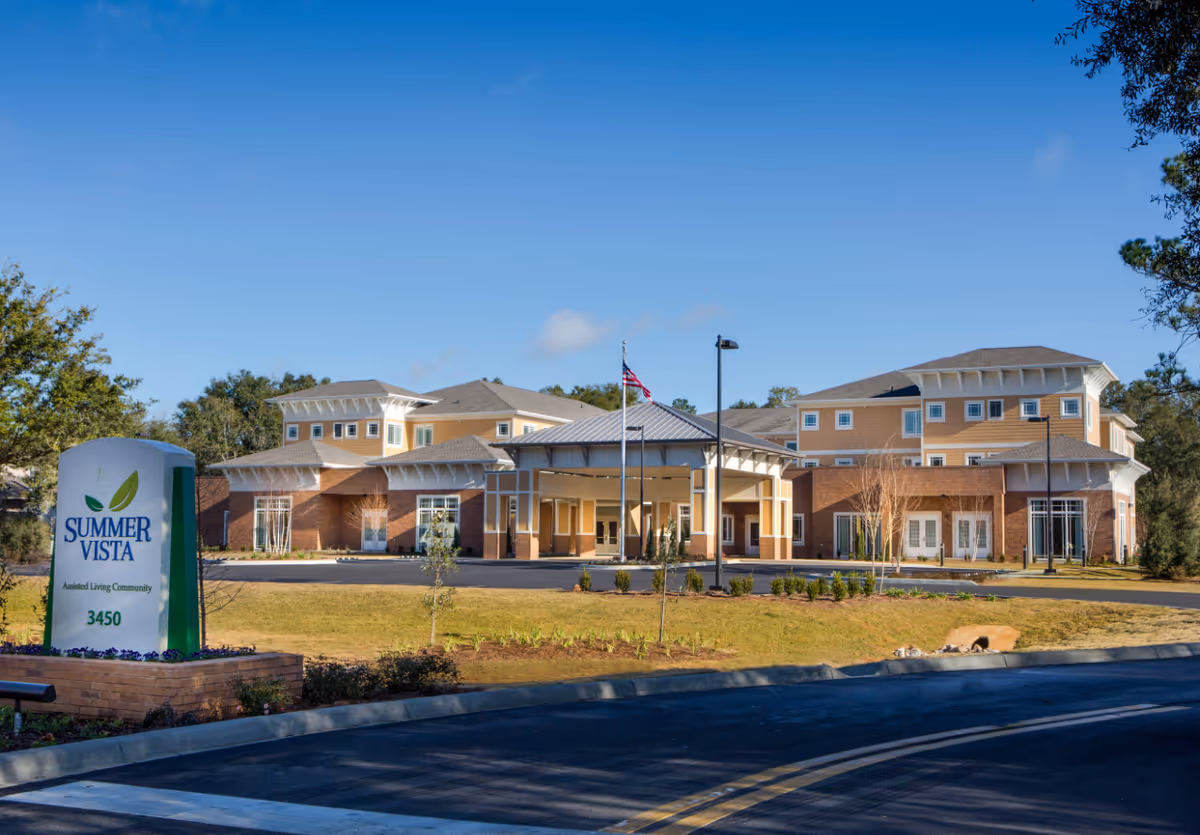 Exterior view of Summer Vista Assisted Living Community building with a clear blue sky, a driveway, and a sign displaying the facility name and address 3450.