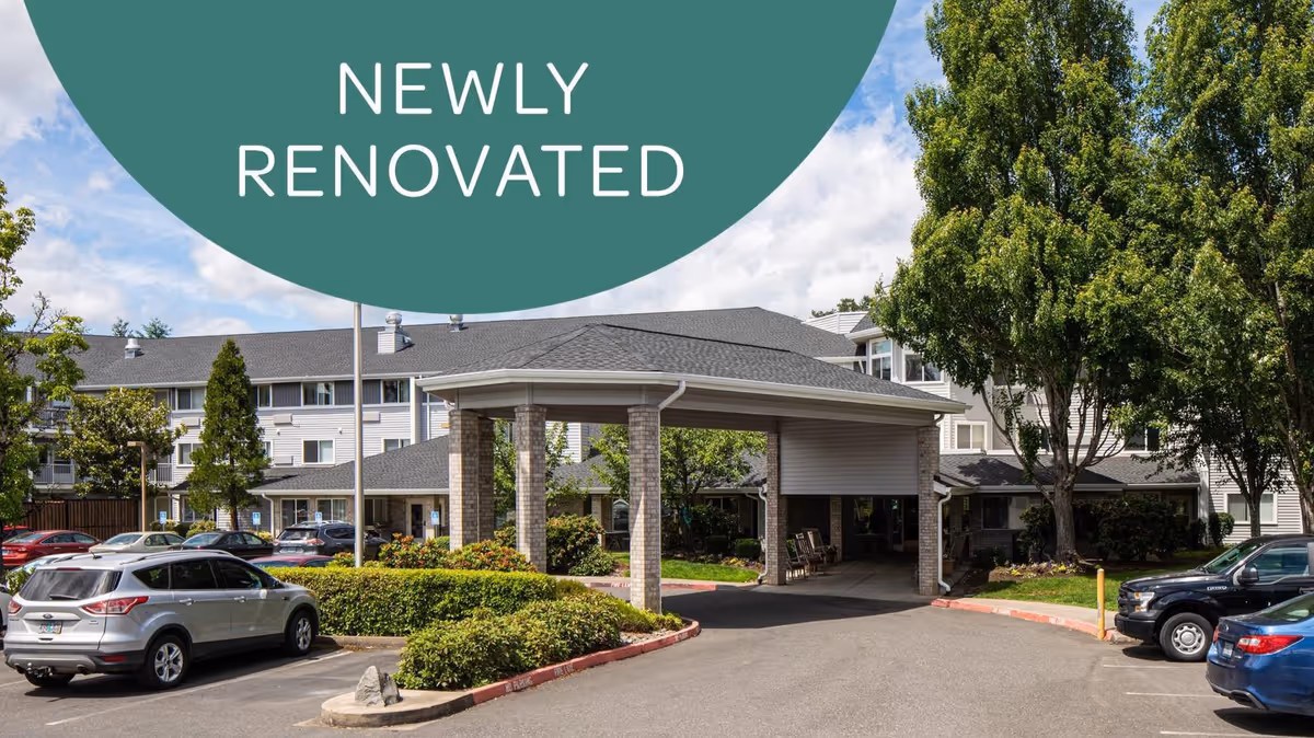 Exterior view of a senior living facility with a covered entrance, surrounded by parked cars and greenery under a partly cloudy sky. A green circular banner with the text 'NEWLY RENOVATED' is overlaid at the top of the image.