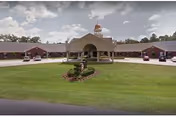 Single-story senior care facility with central arch entrance, circular driveway, and lawn.