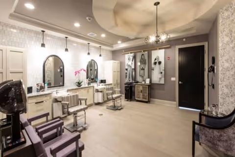 Bright, modern salon-style interior with styling chairs, mirrors, and decorative lighting.