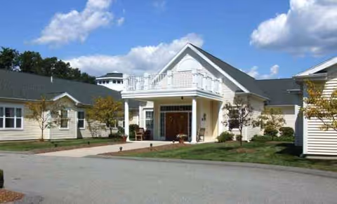 Exterior view of The Atrium at Drum Hill, showing entrance, porch, and landscaped lawn.