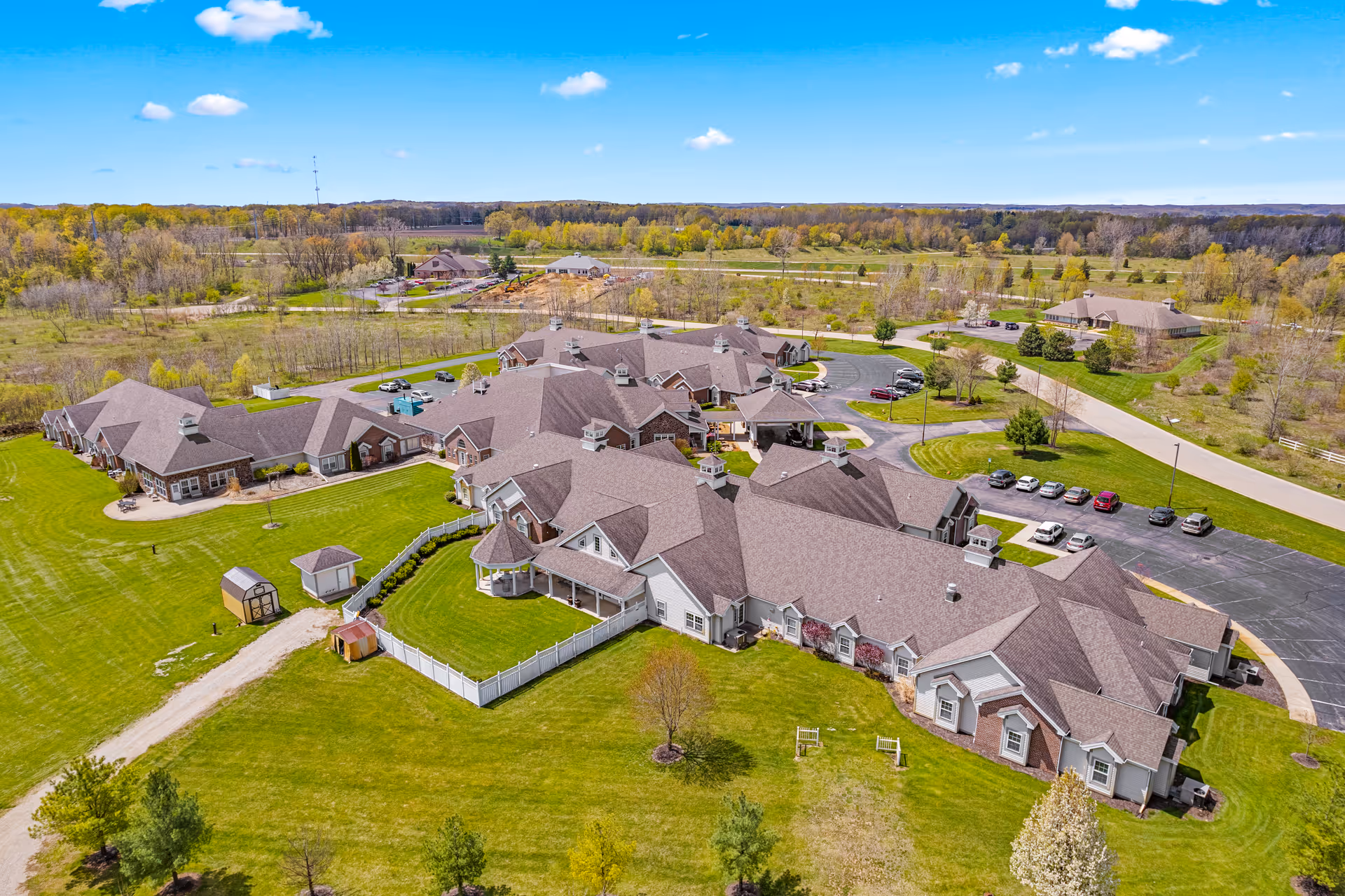 Aerial view of Woodland Terrace at Longmeadow showing multiple connected senior living buildings, parking areas and surrounding green grounds.