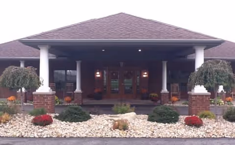 Front entrance of a senior living facility with columns and landscaped rock beds.