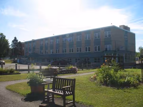 Exterior view of Gogebic Medical Care Facility with benches, lawn, and garden landscaping.