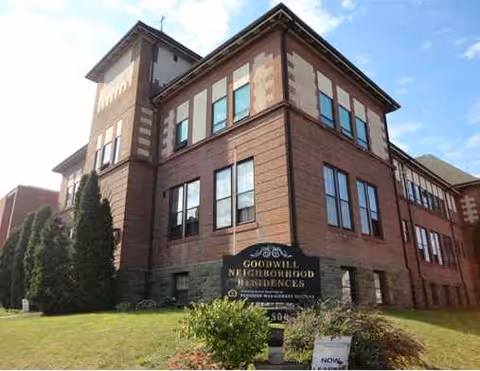 Brick multi-story senior living facility exterior with a Goodwill Neighborhood Residences sign.