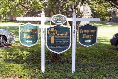 Signs for Cambridge Manor, Georgetown Manor, and the office stand in a grassy front yard.