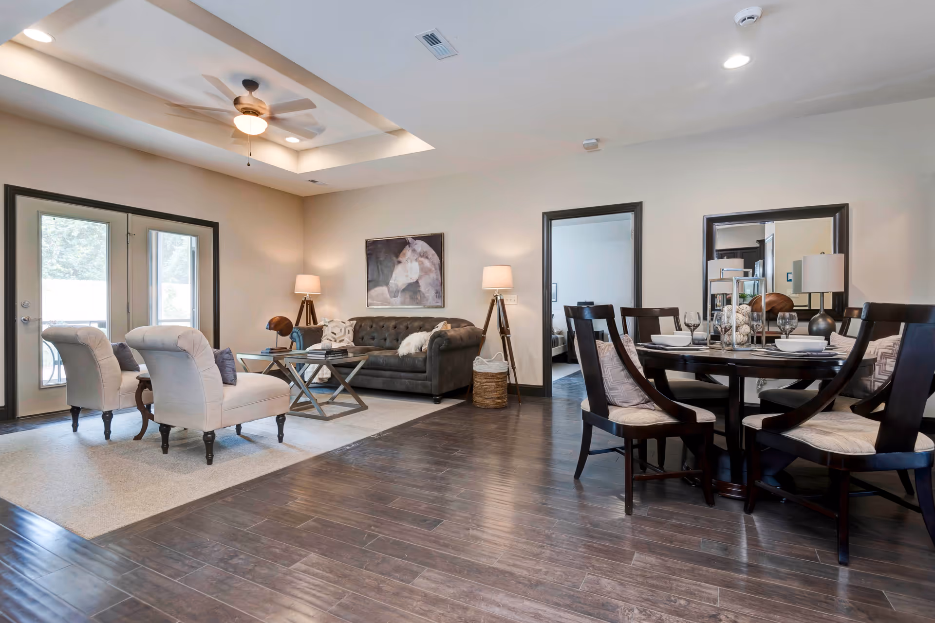 Open-plan living and dining area with a sofa, two armchairs, coffee table, and round dining table on dark wood floors.
