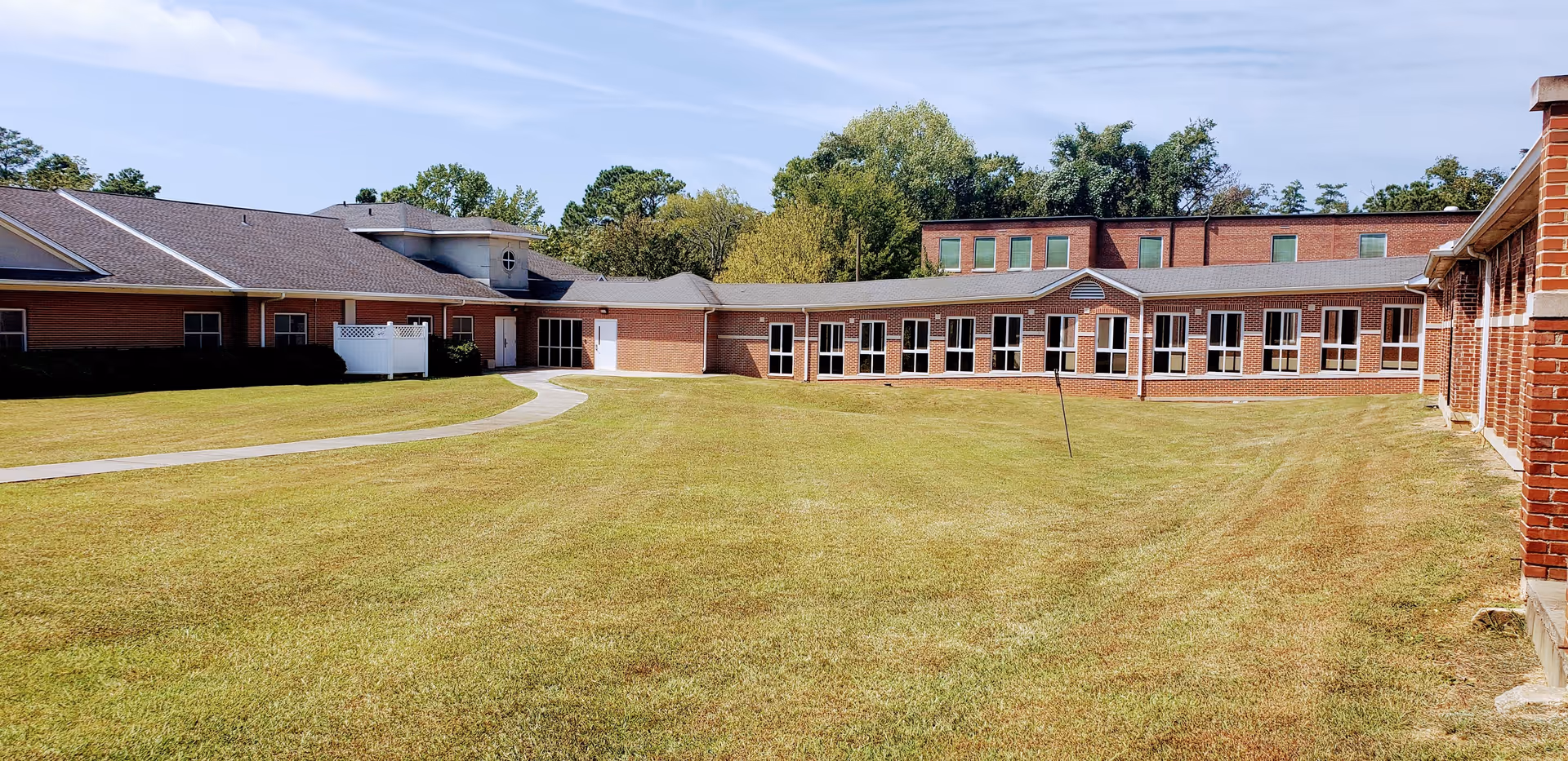 A view of the North Hill Nursing and Rehabilitation facility featuring a spacious lawn and brick buildings.