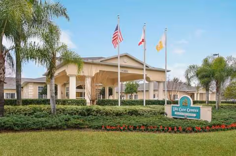 Exterior view of Life Care Center of New Port Richey with flags at the entrance.
