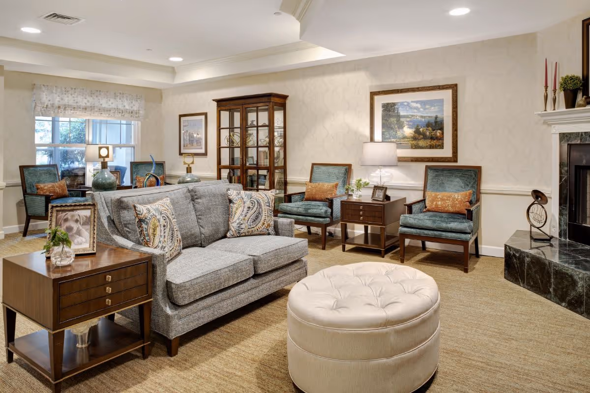 Bright, well-appointed living room with a sofa, armchairs, ottoman, side tables and a fireplace.