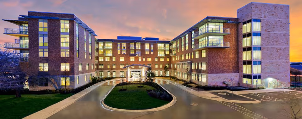 Exterior view of Westminster senior living facility, brick building with illuminated windows and circular driveway.