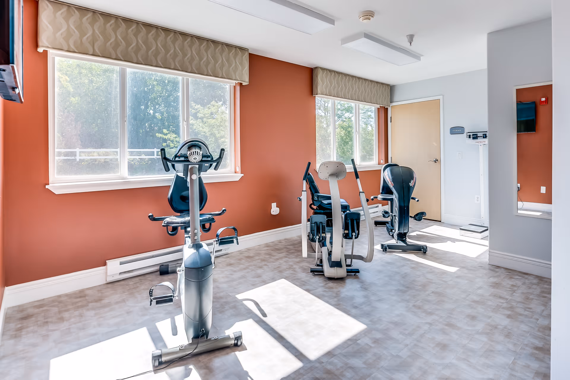 Bright exercise room with stationary bikes and large windows.