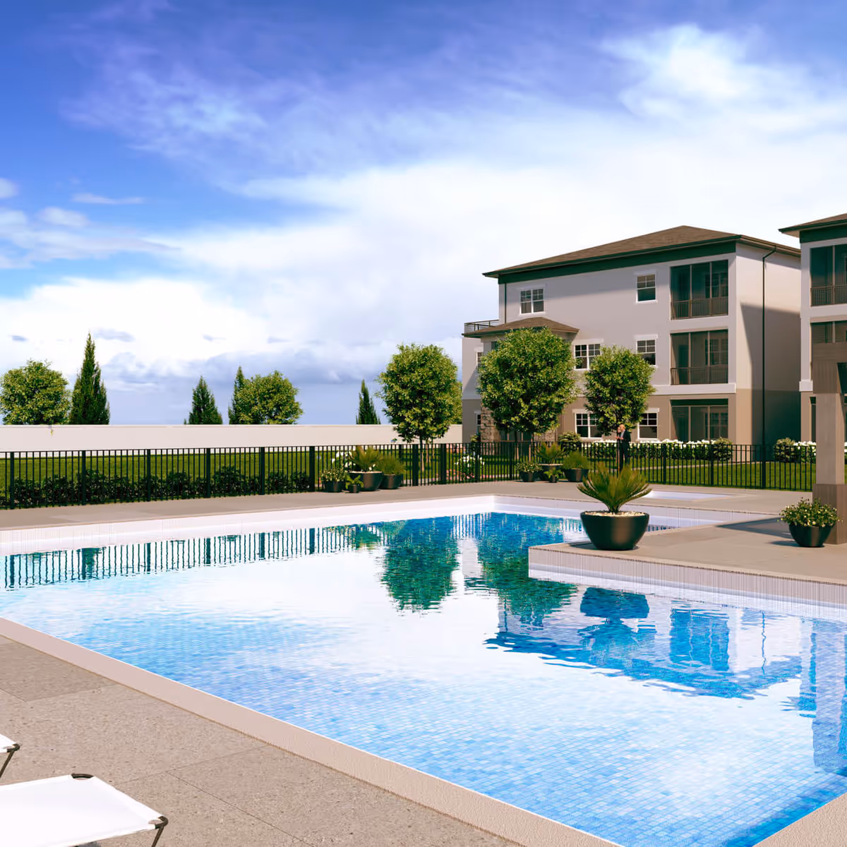 Rectangular outdoor swimming pool beside lounge chairs with a three-story residential building and landscaped trees under a blue sky.
