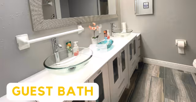 Modern guest bathroom with dual glass vessel sinks and a long vanity.