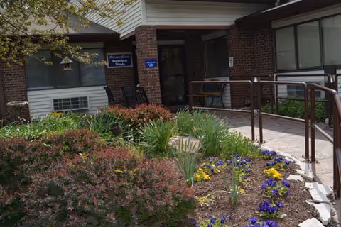 Entrance to Bethlehem Woods Nursing and Rehabilitation with brick exterior and garden landscaping.