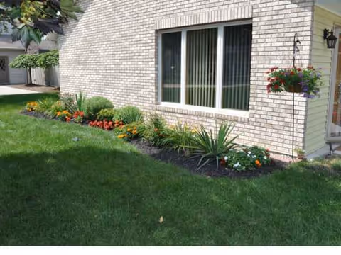 Brick exterior with a flower-lined lawn and window garden along the building.