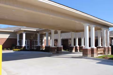 Exterior entrance with a covered drive and white brick columns in front of the facility.