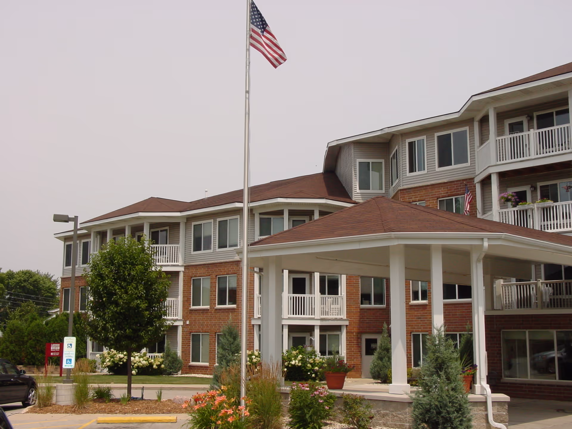 Exterior view of Howard Village Senior Living with flagpole, brick facade, and entrance canopy.