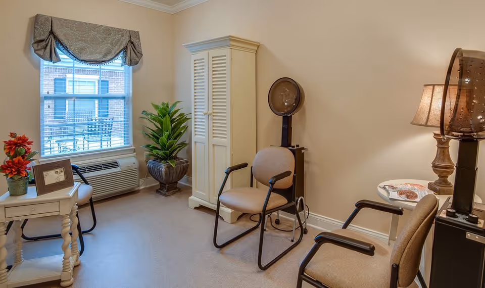 Small salon-style common room with chairs, hair dryer stations, a cabinet, and a window.