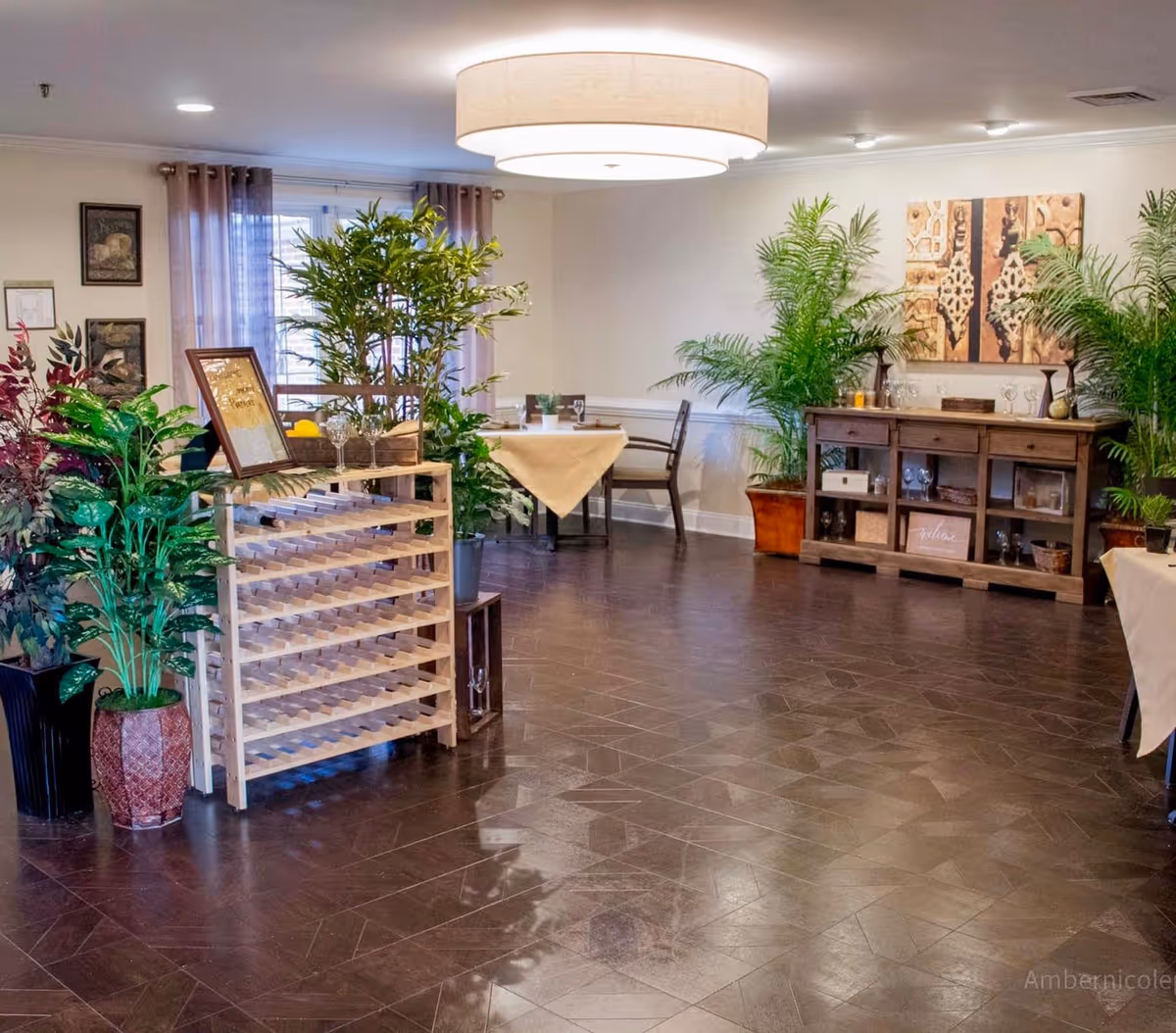 A welcoming interior of a senior living facility featuring plants, tables, and decorative elements.