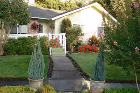 Front exterior of a light-colored, single-story home with a walkway, steps, and landscaped garden.
