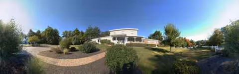 Panoramic view of Serenity Hill Nursing and Rehabilitation Center exterior with a curved driveway and trees.