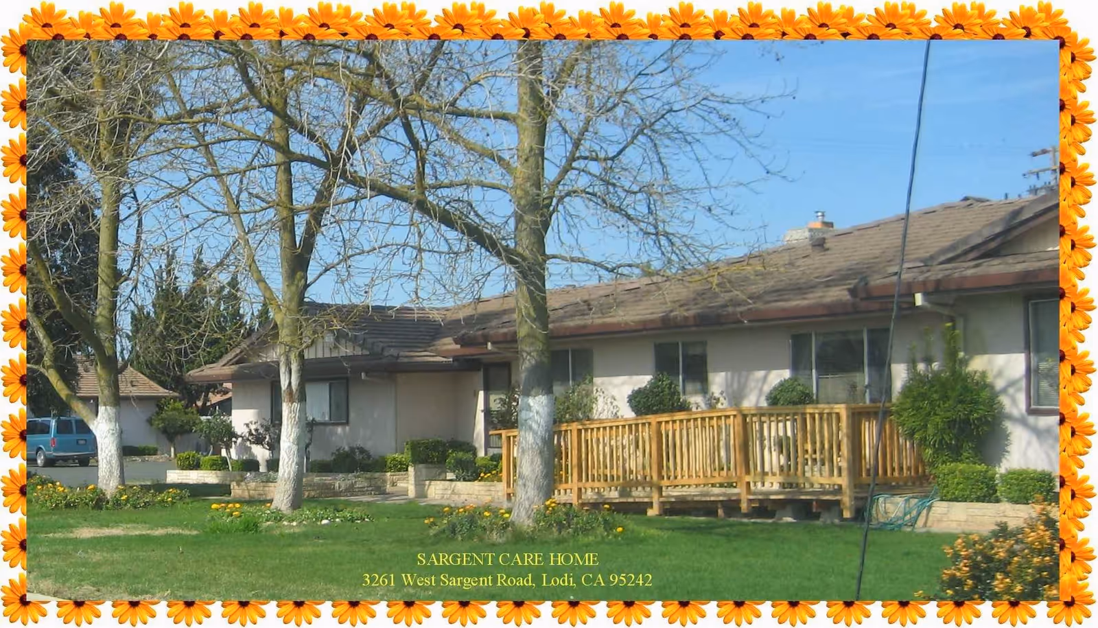 Front exterior of a single-story care home with a wooden wheelchair ramp, lawn and trees, shown with a decorative floral border.
