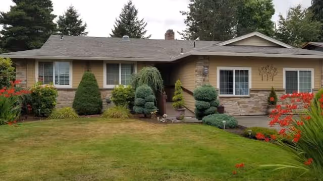 Front exterior of a single-story home with a manicured lawn and trimmed shrubs.
