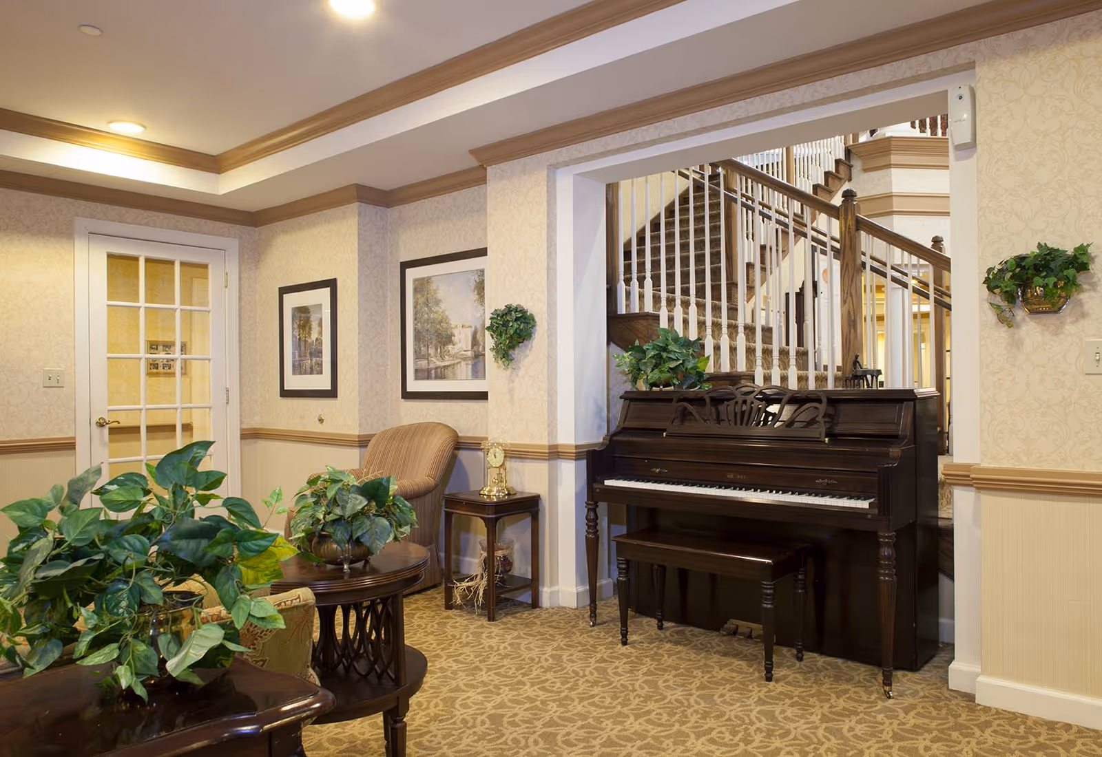 An elegant lounge area with an upright piano, seating, plants, and a staircase in the background.