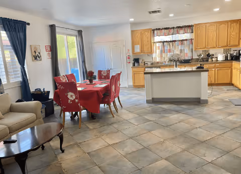 Open living, dining, and kitchen area with red tablecloth, beige sofa, and center island.