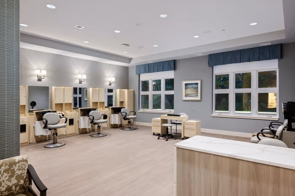 Bright interior salon with multiple styling stations, swivel chairs, mirrors, and large windows.
