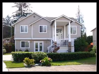 A two-story residential-style senior living facility with a front porch and landscaped lawn.