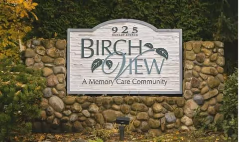 Stone Birch View Memory Care Community sign atop a rock wall with greenery.