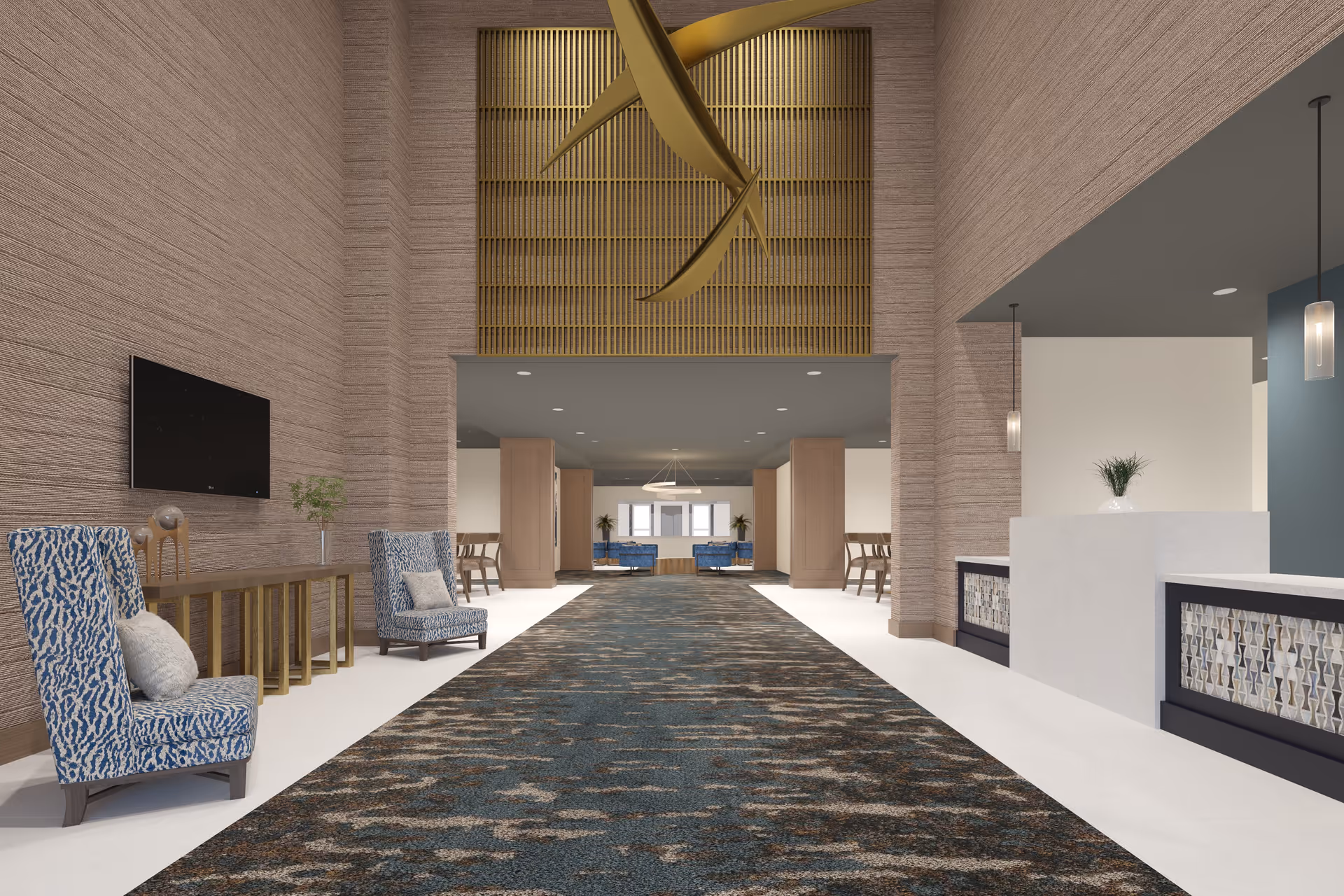 A spacious and modern interior lobby area with high ceilings and textured walls. The space features a long patterned carpet running down the center, two blue patterned armchairs with pillows on the left side, a wooden console table with decorative items, and a wall-mounted flat-screen TV. On the right side, there is a white reception desk with decorative panels and pendant lights hanging from the ceiling. In the background, there are more seating areas with blue chairs and wooden tables.