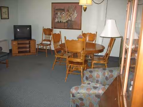 Interior living area in Sheyenne Care Center with round dining table, chairs, sofa, and TV.