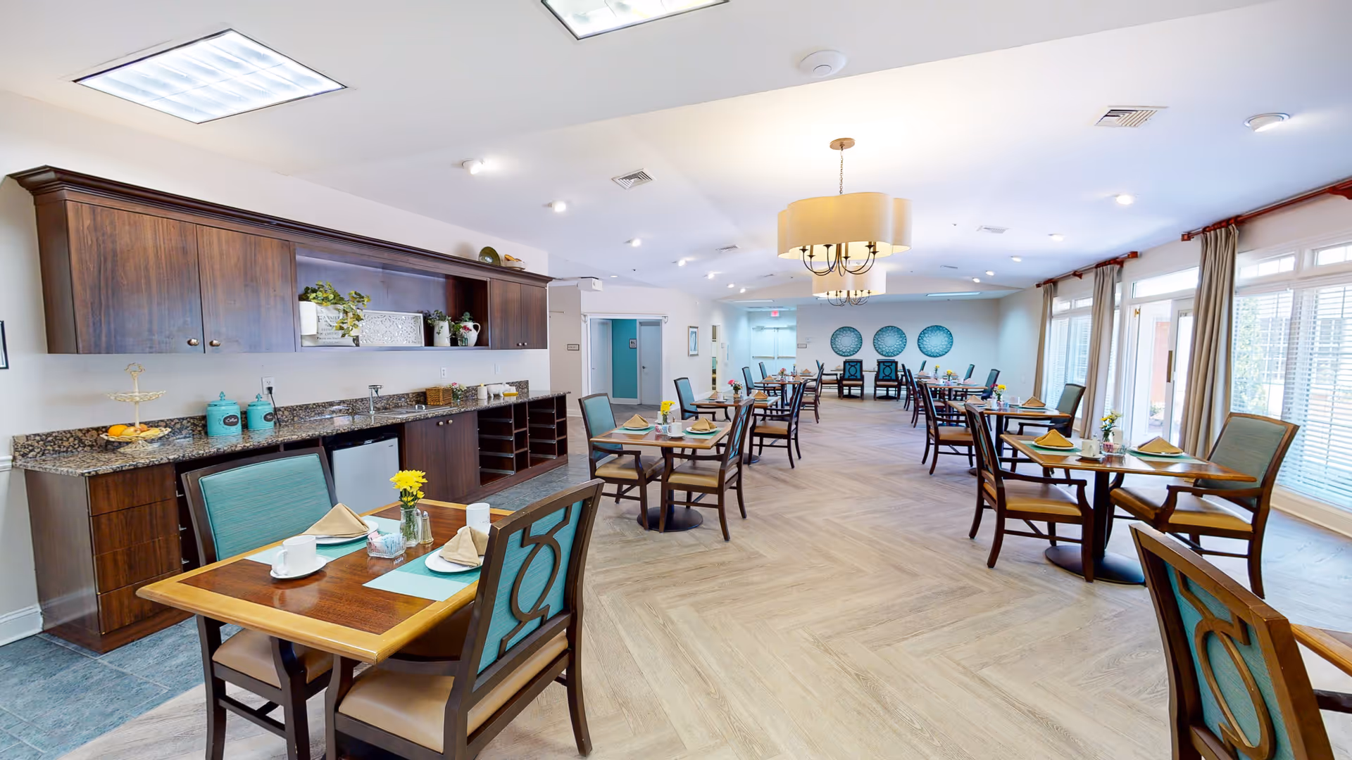 Bright, spacious dining room with multiple set tables and chairs and a buffet counter along one wall.